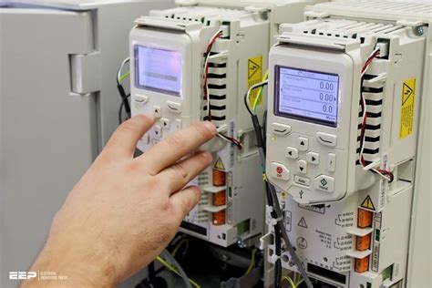 Technician installing a replacement VFD in an industrial control panel